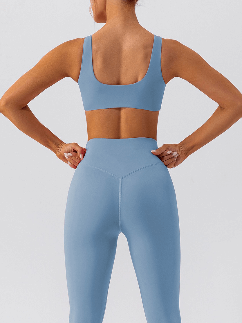 Back view of woman wearing seamless blue gym sports bra and leggings, showing breathable workout attire for female athletes.